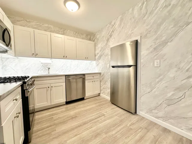 a kitchen with stainless steel appliances kitchen island granite countertop a refrigerator and a stove top oven