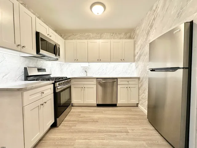 a kitchen with granite countertop white cabinets and appliances