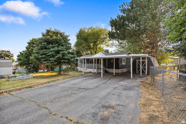 271 Mindella Way Layton, UT 84041 - Photo 2 of 27 Property exterior featuring a covered carport, elevated porch, dark-toned siding, and a fenced side yard