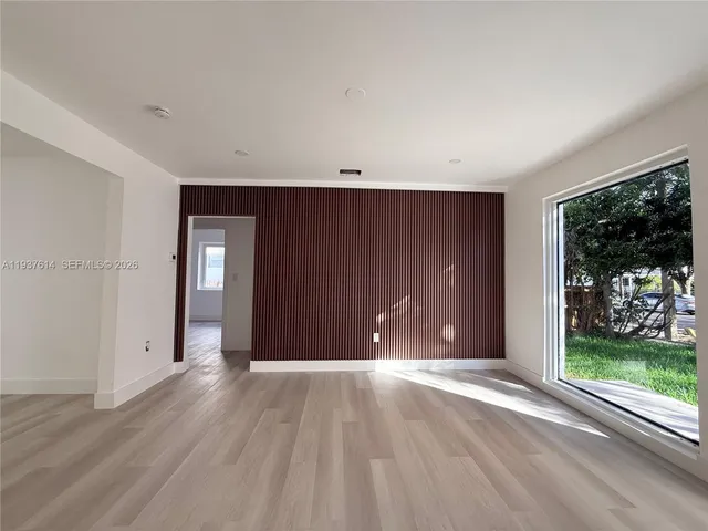a view of an empty room with wooden floor and windows