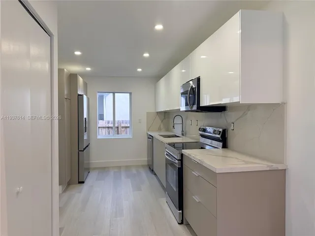 a kitchen with a sink a counter top space stainless steel appliances and cabinets