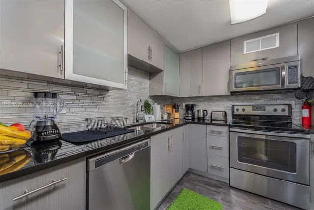 a kitchen with stainless steel appliances granite countertop a sink a stove and cabinets