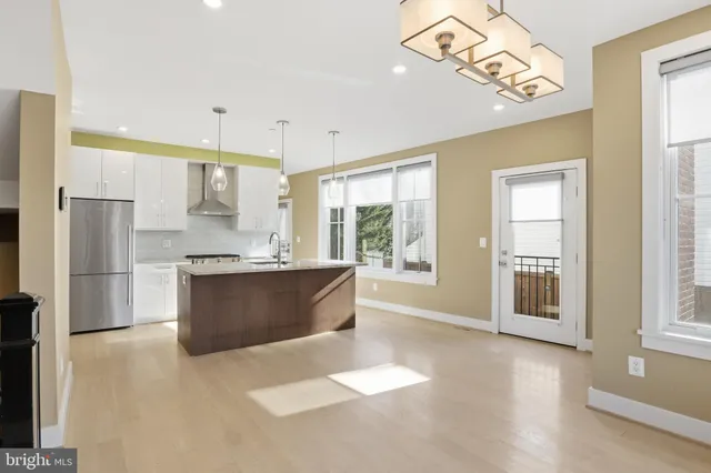 a large kitchen with kitchen island a large counter top space a sink stainless steel appliances and cabinets