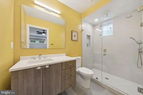 a bathroom with a granite countertop sink toilet a mirror and shower