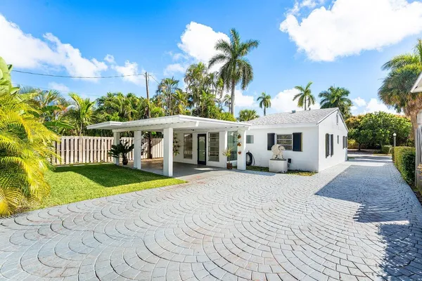 a view of a white house with a yard and potted plants