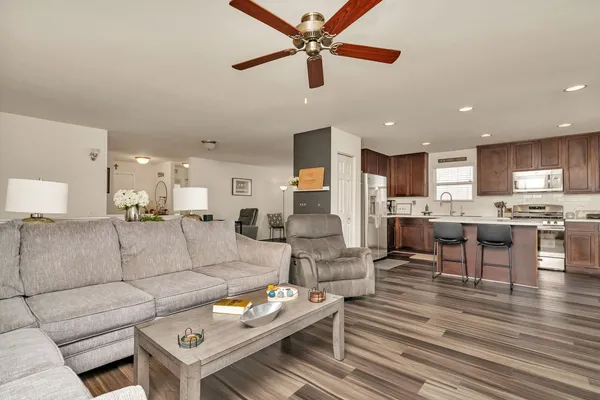 a living room with furniture kitchen view and a wooden floor