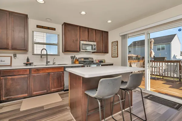 a kitchen with stainless steel appliances granite countertop a sink a stove a refrigerator cabinets and a dining table with wooden floor