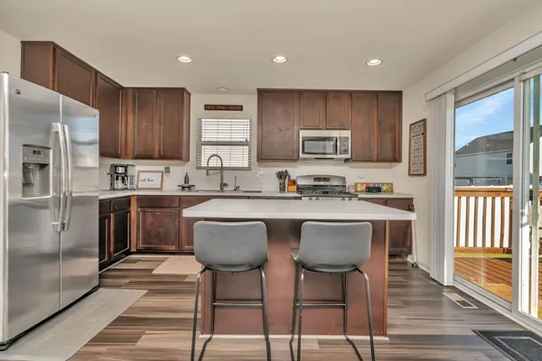a kitchen with stainless steel appliances granite countertop a stove a sink dishwasher a refrigerator and a microwave oven with wooden floor