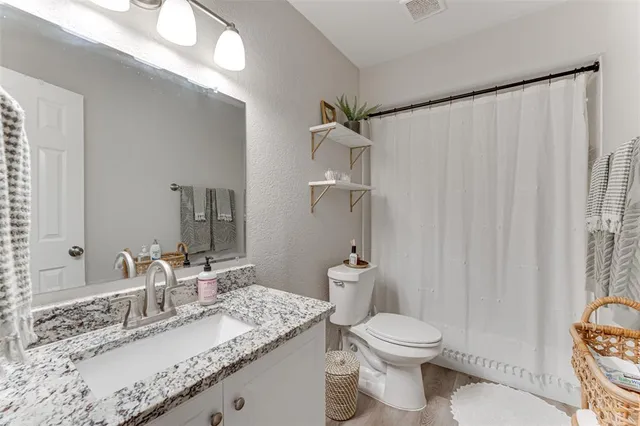 a bathroom with a granite countertop sink toilet and a mirror
