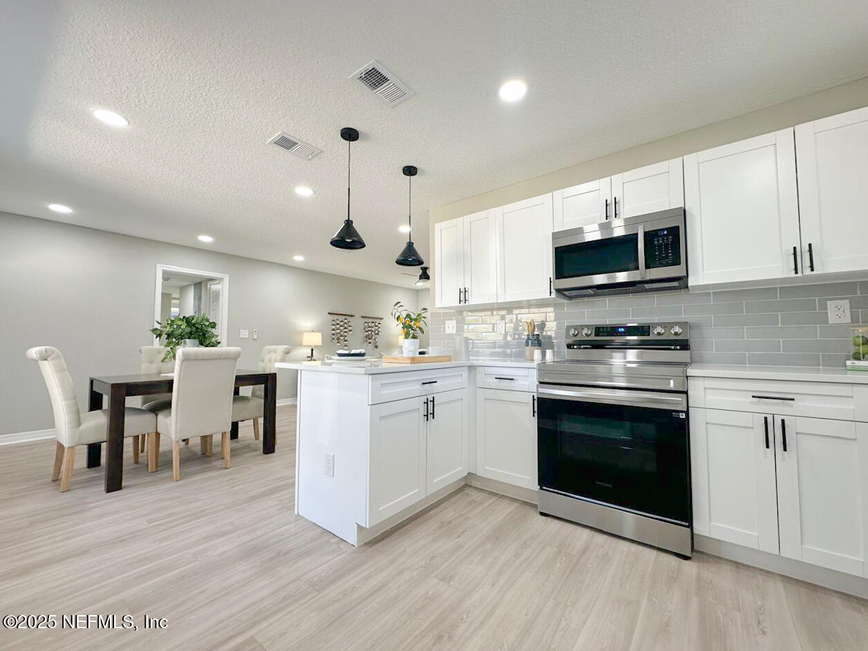 1336 Morgana Road Jacksonville, FL 32211 - Photo 1 of 36 a kitchen with granite countertop a stove top oven a sink dishwasher a dining table and chairs with wooden floor