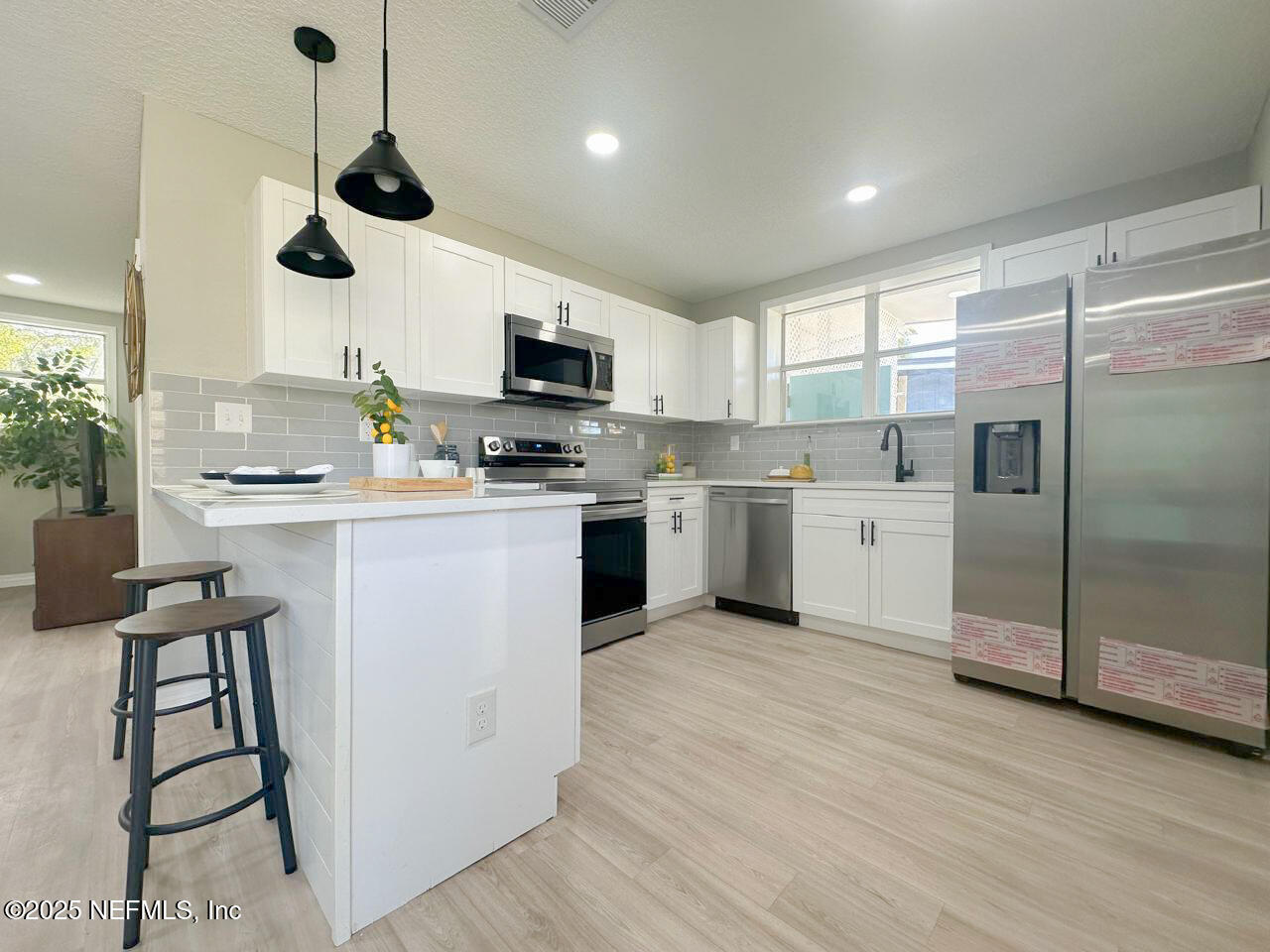 1336 Morgana Road Jacksonville, FL 32211 - Photo 6 of 36 a kitchen with stainless steel appliances a microwave a stove a sink dishwasher a refrigerator and white cabinets with wooden floor