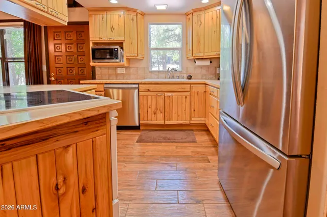 a kitchen with stainless steel appliances granite countertop a refrigerator a sink dishwasher and wooden cabinets with wooden floor