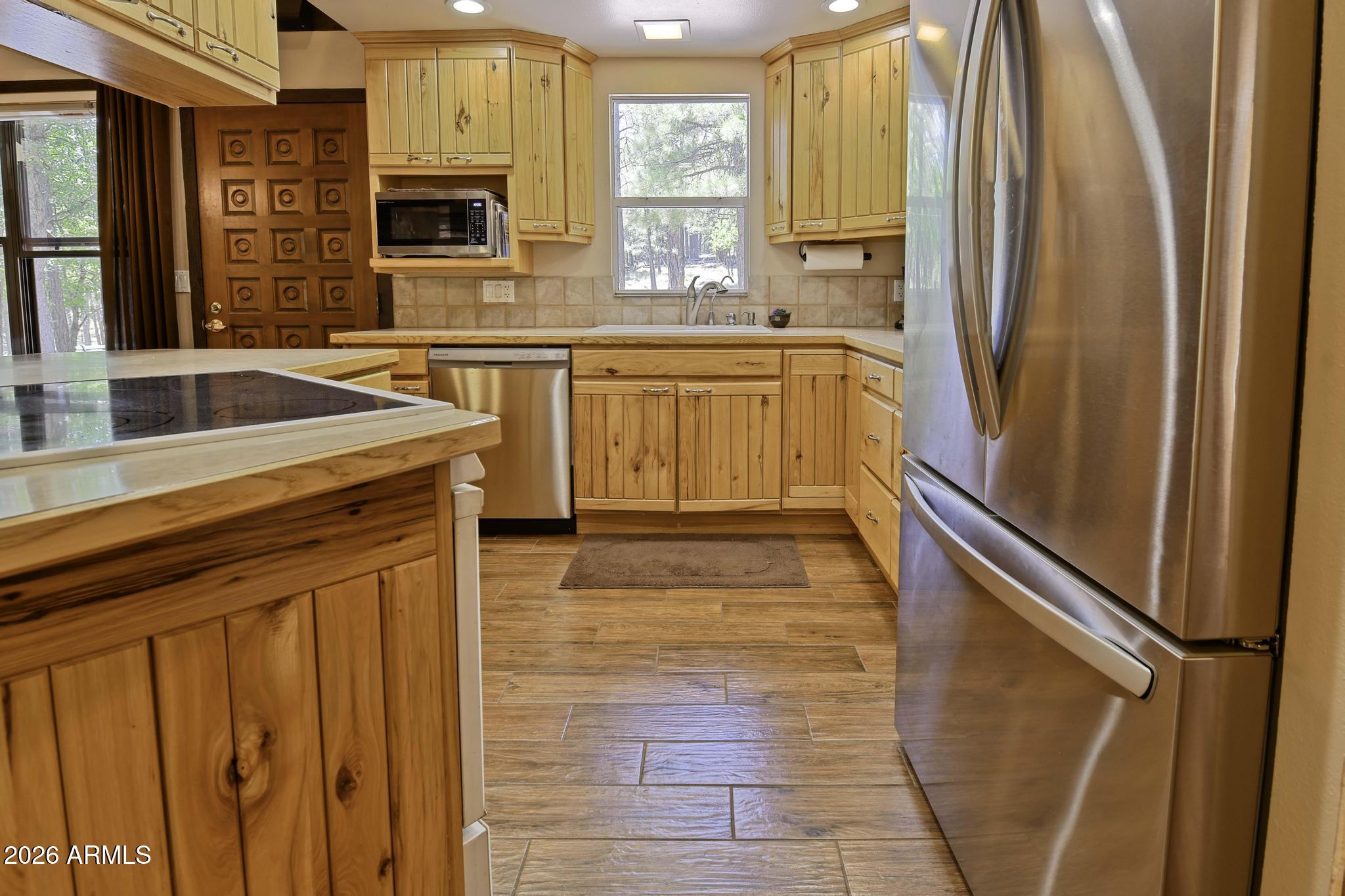 1018 Reata Pass Happy Jack, AZ 86024 - Photo 10 of 33 a kitchen with stainless steel appliances granite countertop a refrigerator a sink dishwasher and wooden cabinets with wooden floor