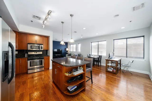 a large kitchen with kitchen island a large counter top stainless steel appliances and cabinets