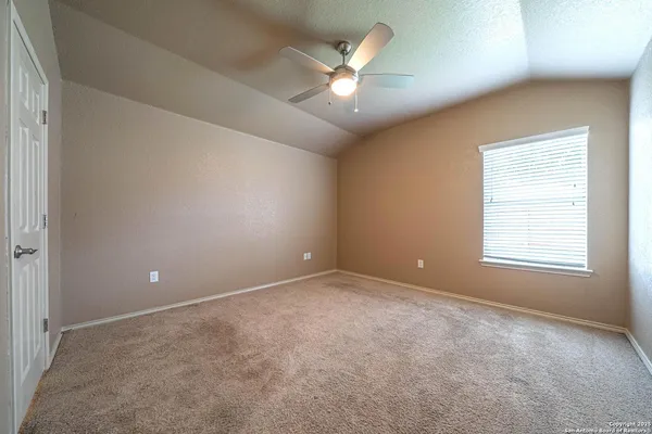 an empty room with a ceiling fan and window