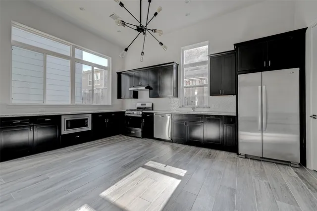 a kitchen with stainless steel appliances granite countertop a refrigerator a sink a stove and oven