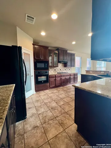 a kitchen with stainless steel appliances granite countertop a refrigerator and a stove top oven
