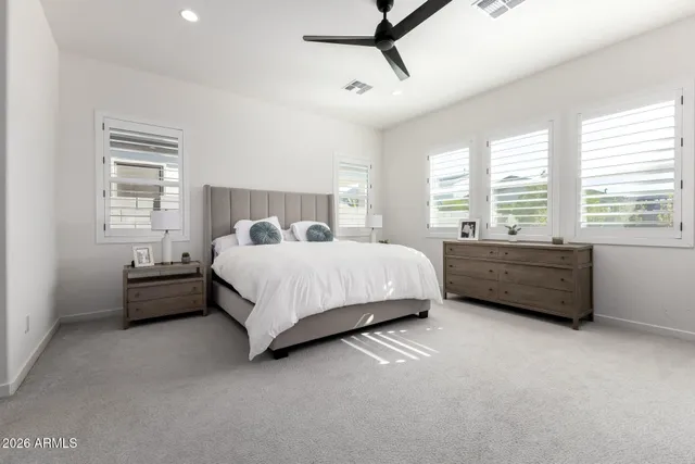 a spacious bedroom with a bed a couch and a ceiling fan