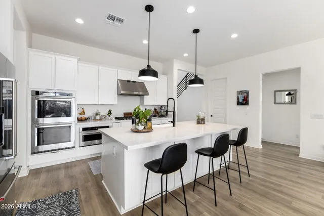 a kitchen with stainless steel appliances kitchen island granite countertop a stove a sink dishwasher and a refrigerator with wooden floor