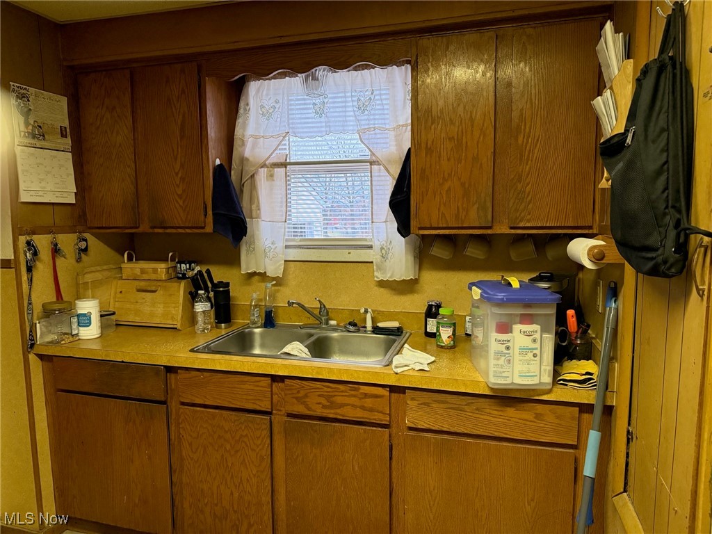 1311 Warner Road Southeast Canton, OH 44707 - Photo 3 of 14 Kitchen featuring light countertops, water heater, and brown cabinets