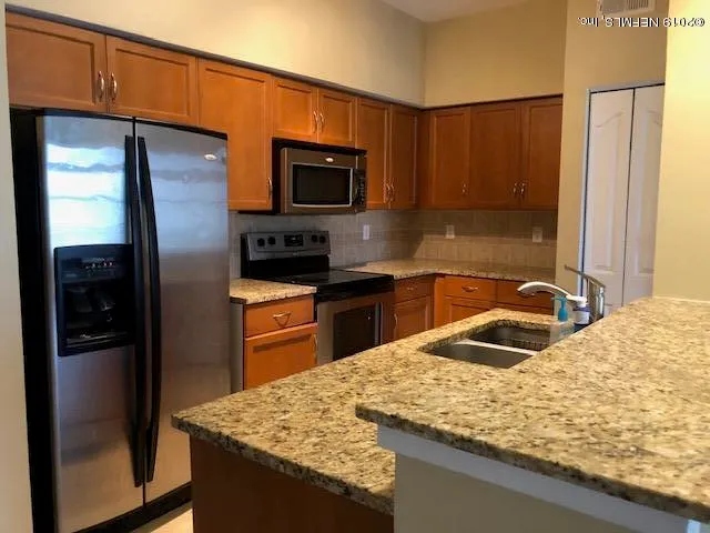 a kitchen with stainless steel appliances granite countertop a sink refrigerator and microwave
