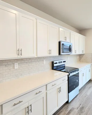a kitchen with granite countertop white cabinets and white appliances