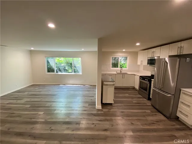 a view of a kitchen with a sink refrigerator and wooden floor