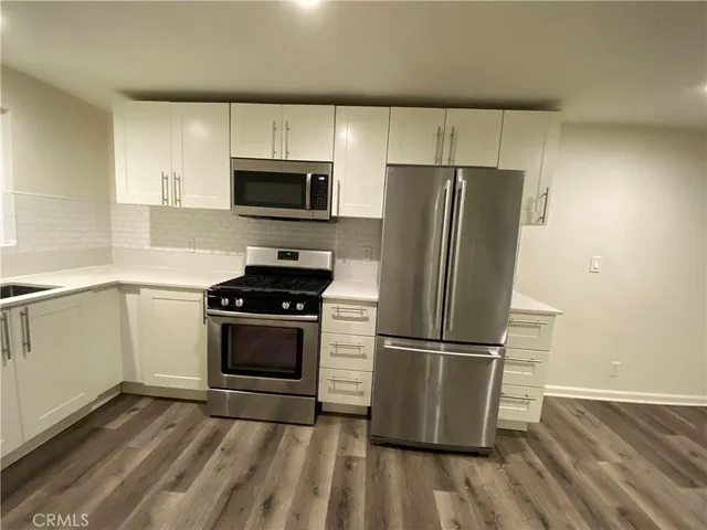 a kitchen with wooden floors and stainless steel appliances