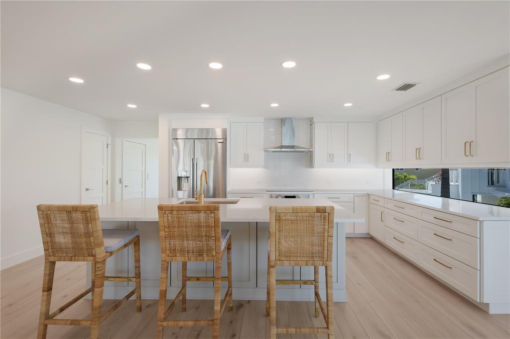 204 Waterway Avenue Boca Grande, FL 33921 - Photo 6 of 49 a kitchen with stainless steel appliances kitchen island granite countertop a dining table chairs and white cabinets