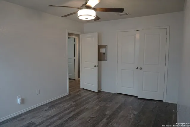 an empty room with wooden floor and ceiling fan