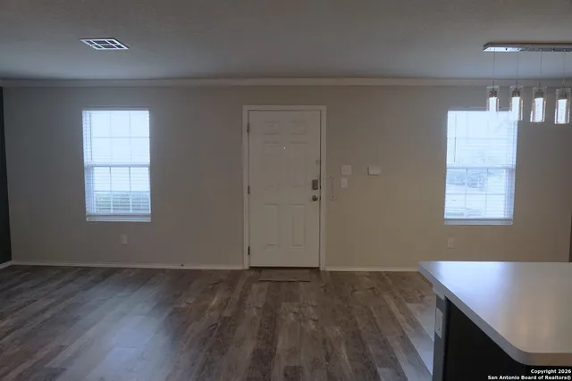 an empty room with wooden floor and windows