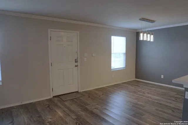 a view of an empty room with wooden floor and a window