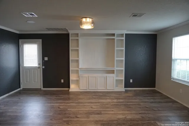 an empty room with wooden floor and windows