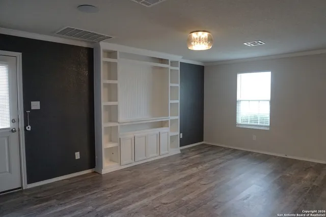an empty room with wooden floor and windows