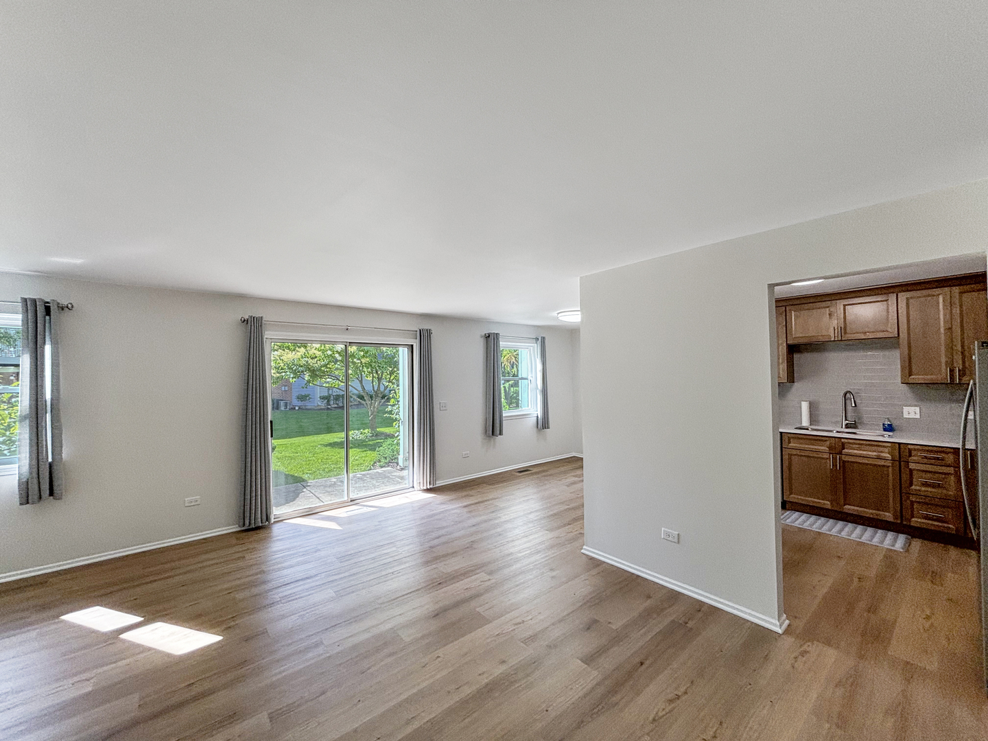 71 Larch Court, Unit B Schaumburg, IL 60193 - Photo 2 of 14 a view of a kitchen and an empty room with wooden floor and a window