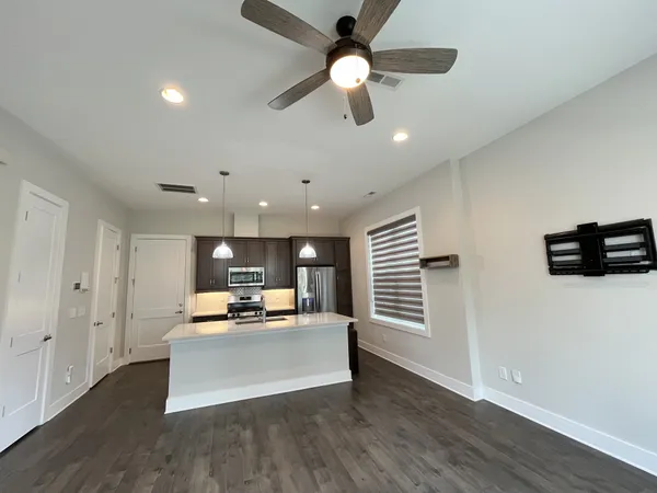 a living room with stainless steel appliances kitchen island furniture and a ceiling fan