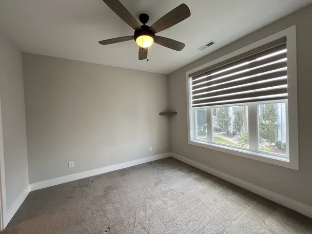 an empty room with windows and ceiling fan