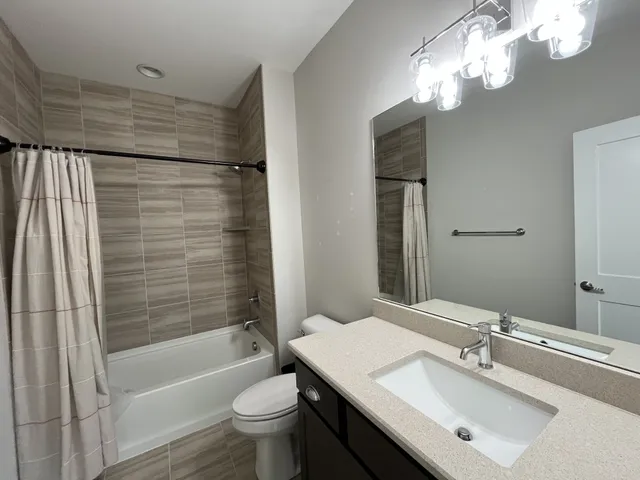 a bathroom with a bathtub shower sink vanity and toilet