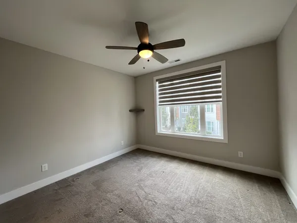 an empty room with windows and fan