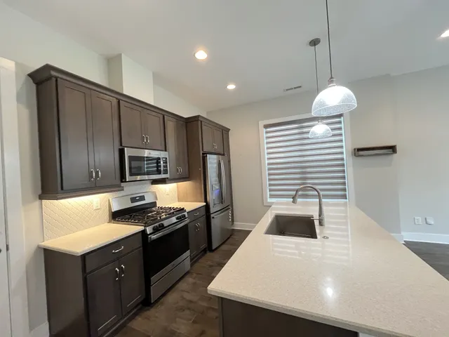a kitchen with kitchen island granite countertop a sink stainless steel appliances and cabinets