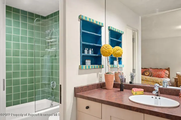 a bathroom with a granite countertop sink a mirror and shower