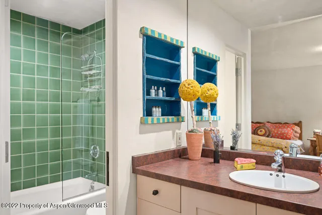 a bathroom with a granite countertop sink a mirror and shower