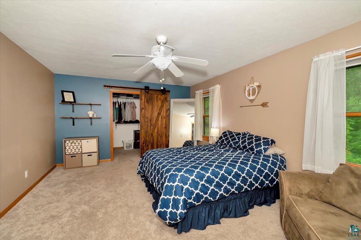5992 Birchway Road Duluth, MN 55810 - Photo 12 of 36 Carpeted bedroom with ceiling fan, a barn door, and a closet