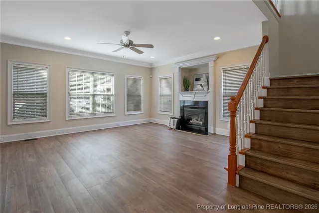 a view of an empty room with wooden floor fireplace and a window