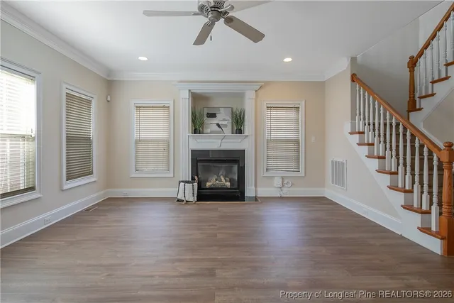 a view of an empty room with wooden floor fireplace and a window