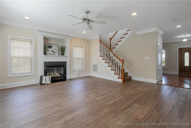 a view of an empty room with wooden floor and a ceiling fan