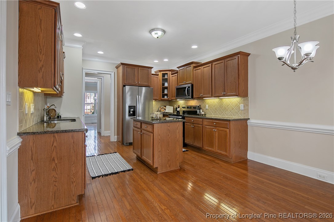 2721 Plum Ridge Road Fayetteville, NC 28306 - Photo 15 of 50 a kitchen with kitchen island granite countertop wooden floors stainless steel appliances a sink and a refrigerator