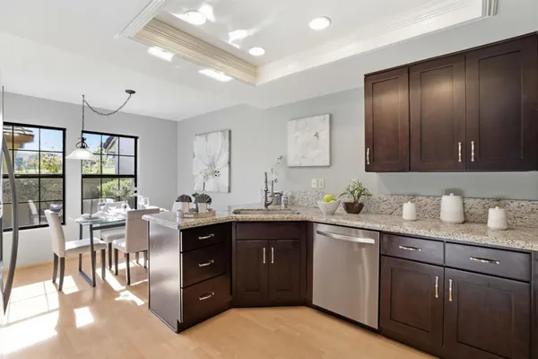 a kitchen with stainless steel appliances granite countertop a refrigerator a sink a stove a dining table and chairs