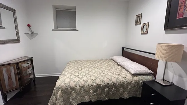 a bedroom with a bed and a lamp on the dresser
