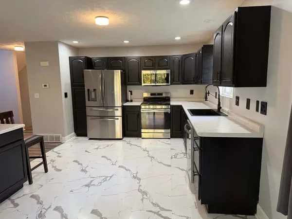 a kitchen with stainless steel appliances kitchen island granite countertop a refrigerator and a sink